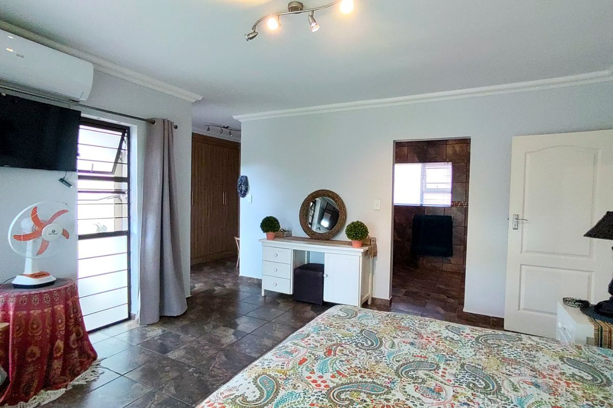 Spacious bedroom featuring tiled flooring, built-in cupboards, a split-system air conditioner, and direct access to an en-suite bathroom.
