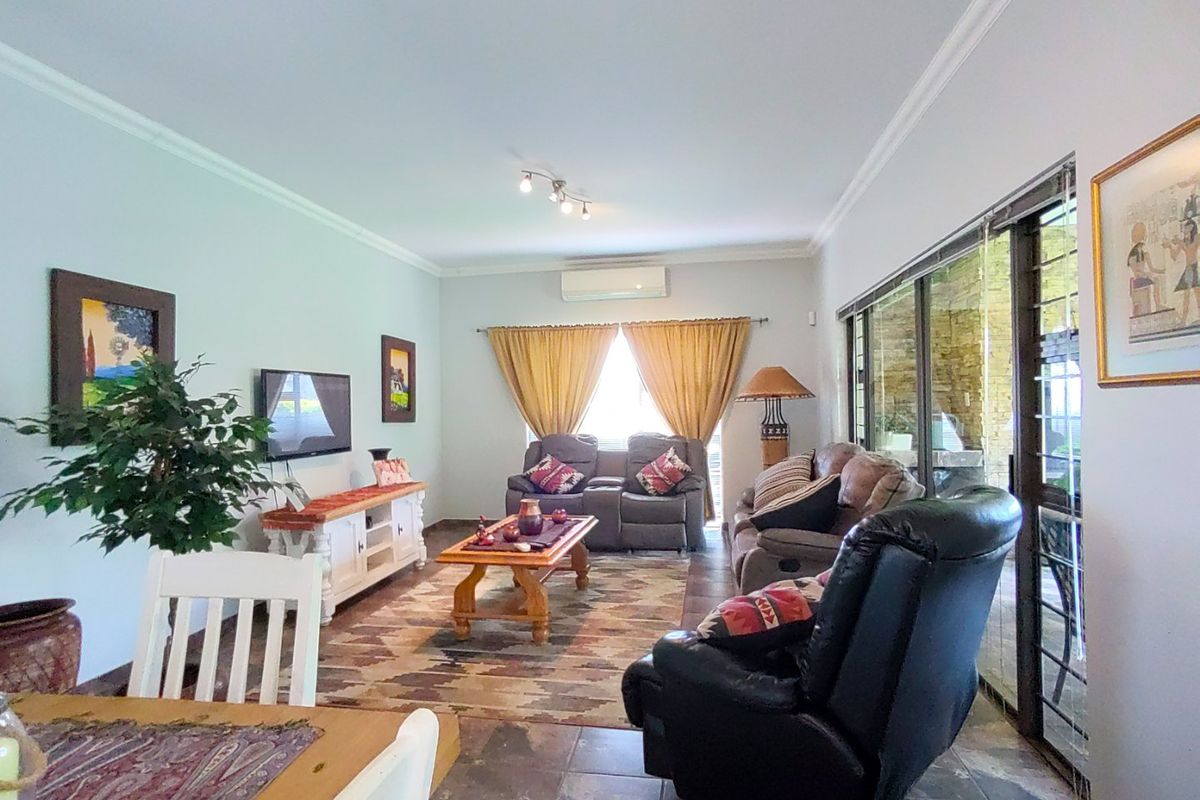A comfortable living room featuring tiled flooring, crown molding, and large sliding glass doors that provide natural light and access to the outdoor area.