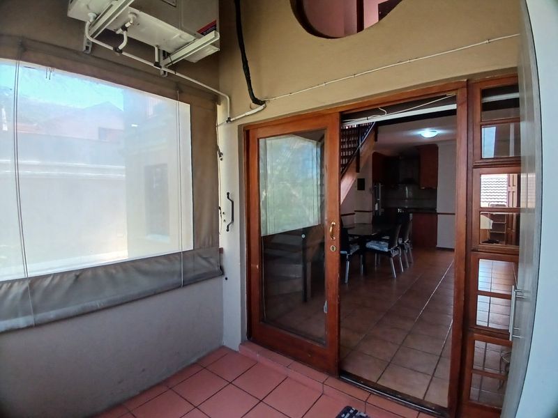 Covered patio area featuring tiled flooring, a wall-mounted air conditioning unit, and a sliding glass door providing access to the interior living space.