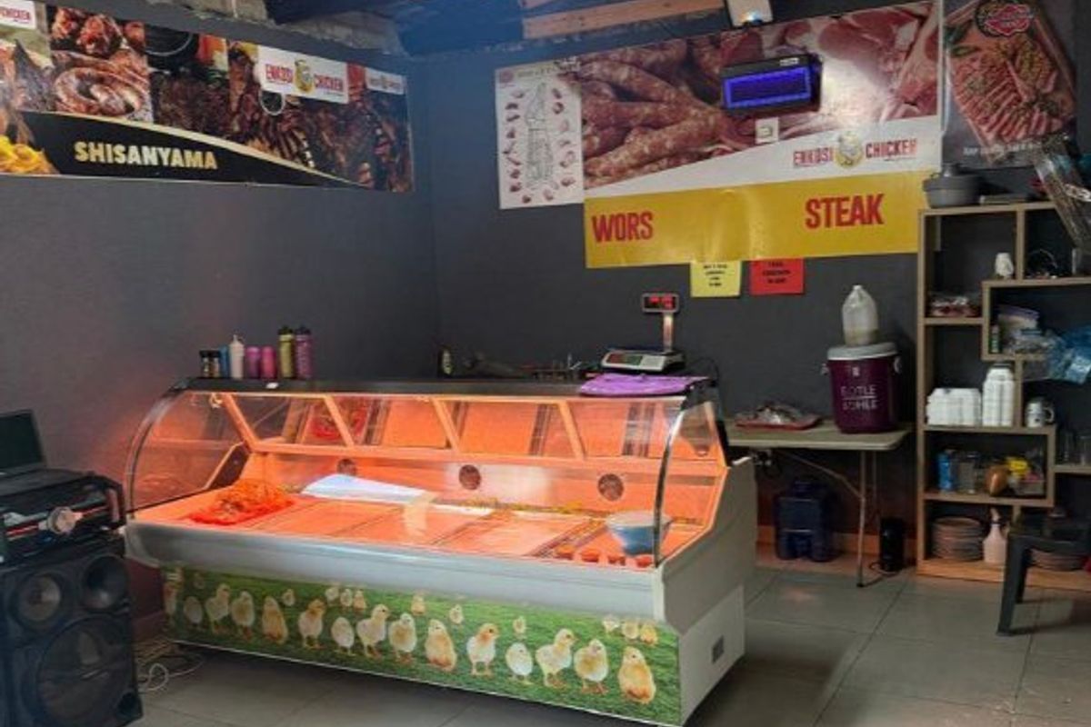 Commercial food preparation and retail space featuring a refrigerated display counter, tiled flooring, and exposed timber roof structure.