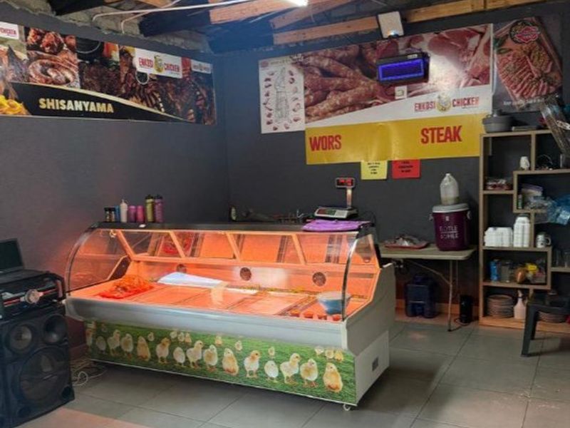 Commercial food preparation and retail space featuring a refrigerated display counter, tiled flooring, and exposed timber roof structure.