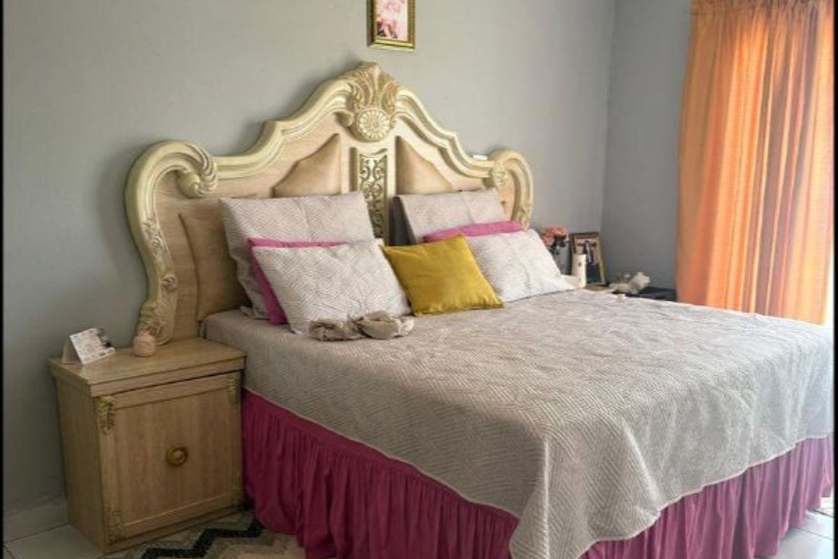 A bedroom featuring tiled flooring, crown molding, and a wall-mounted split-system air conditioning unit.