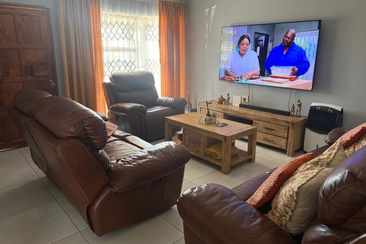 A comfortable living room featuring tiled flooring, a secure window with a metal gate, and a solid wooden door.