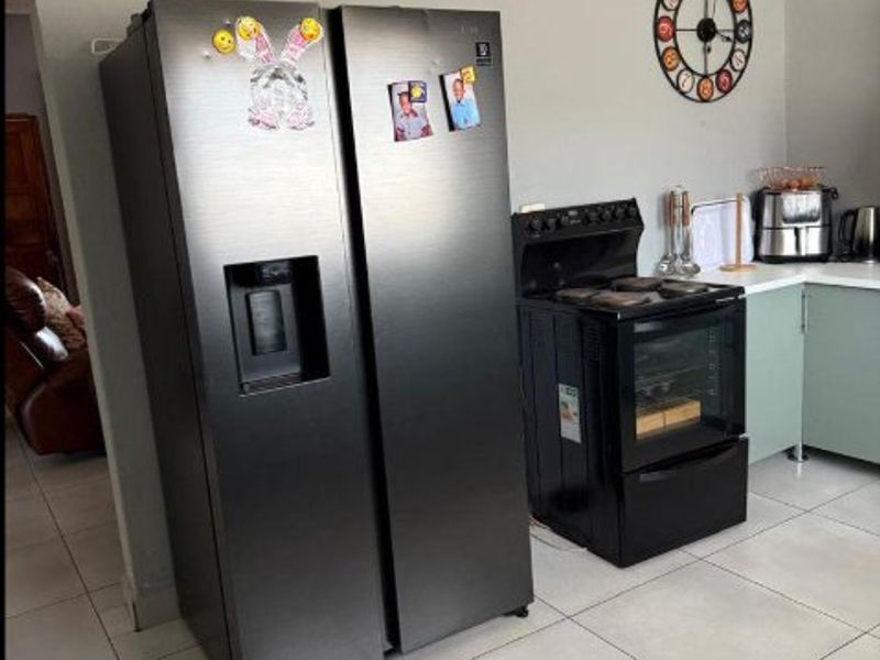 A functional kitchen area featuring tiled flooring, built-in cabinetry, and a freestanding oven and hob.