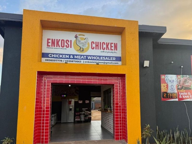 Front entrance of a commercial chicken and meat wholesaler featuring a prominent yellow archway, red tiled entrance detail, and clear business signage.