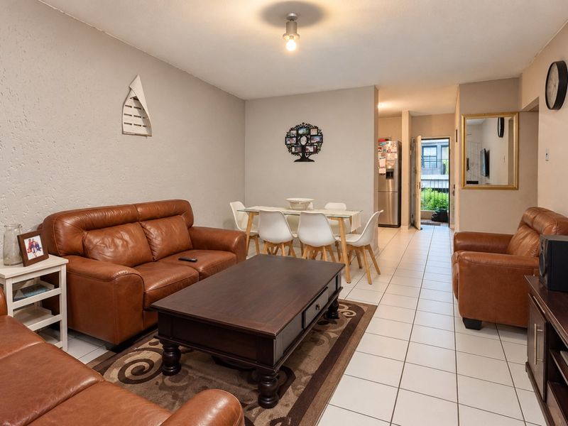 Open plan living and dining area featuring tiled flooring and neutral wall finishes, with direct access to an outdoor balcony.