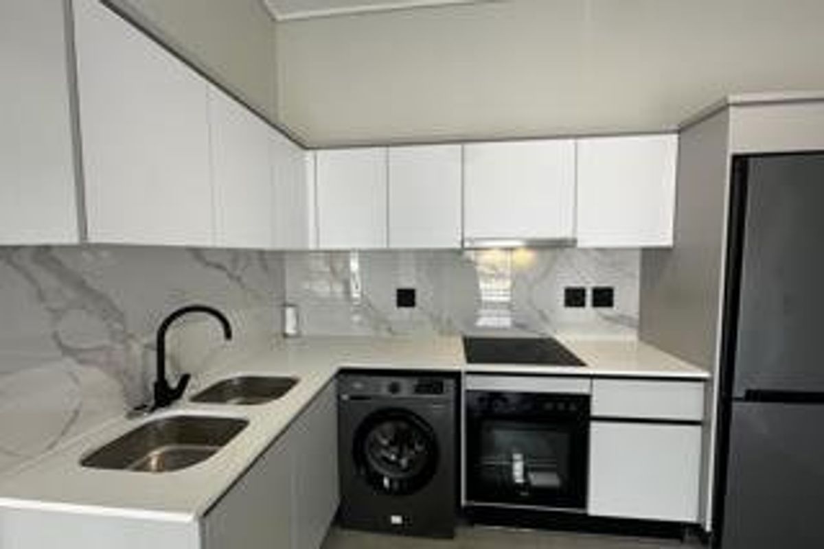Modern kitchen featuring white gloss cabinetry, marble-look splashback, stone countertops, and integrated appliances including an oven, hob, and extractor fan.
