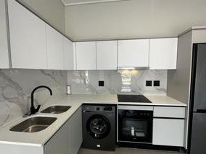 Modern kitchen featuring white gloss cabinetry, marble-look splashback, stone countertops, and integrated appliances including an oven, hob, and extractor fan.