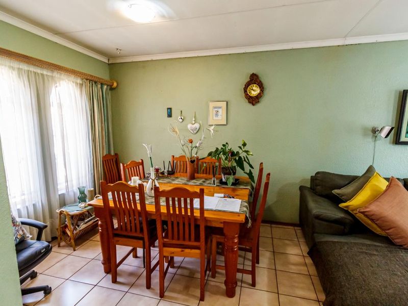 A functional dining area featuring tiled flooring and large windows with curtain rails, providing a comfortable space for family meals.