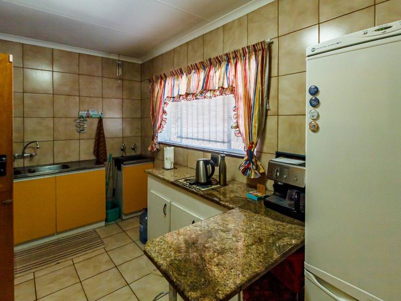 A functional kitchen featuring granite countertops, tiled wall finishes, and built-in cabinetry with a stainless steel sink and mixer tap.