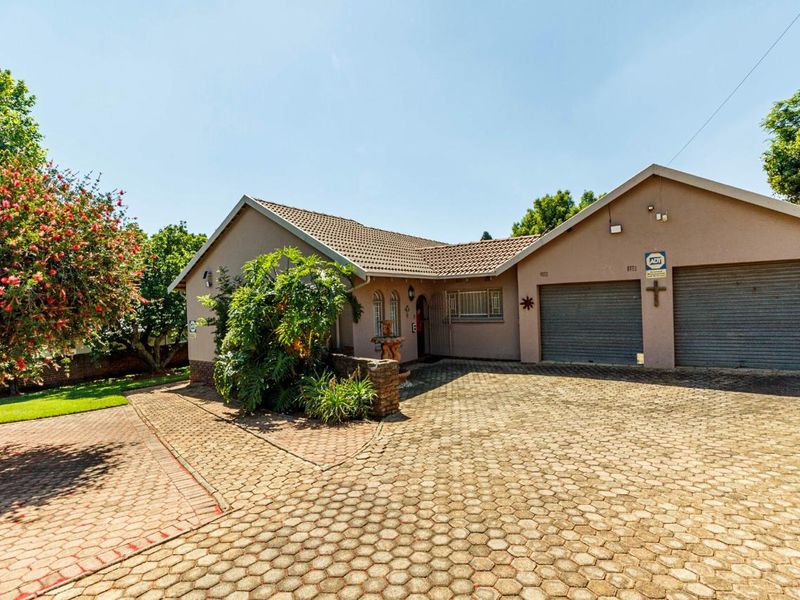 Front elevation of a single-story house featuring a paved driveway, double garage, and established garden area.