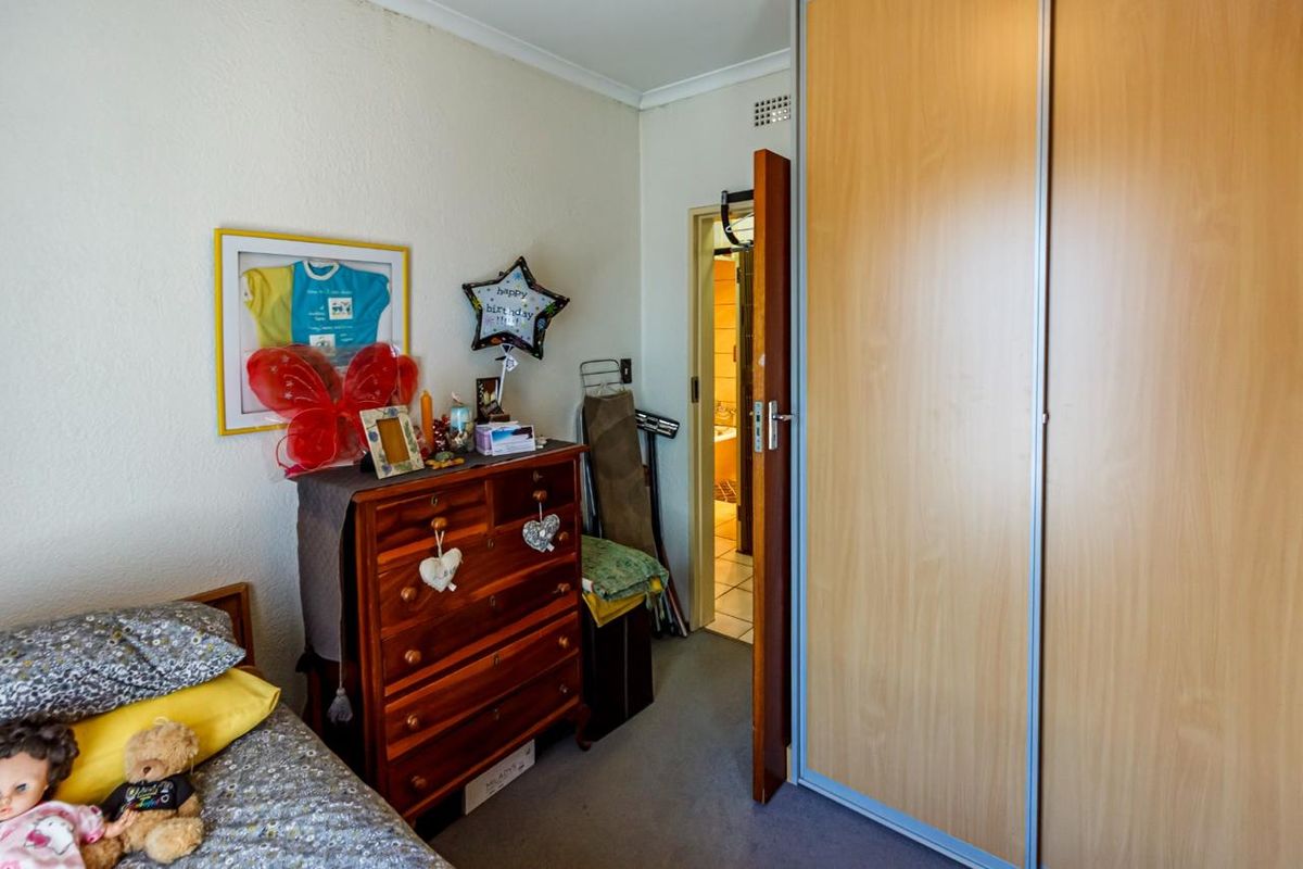 A bedroom featuring a built-in wardrobe with light wood-finish sliding doors and access to an adjoining bathroom.