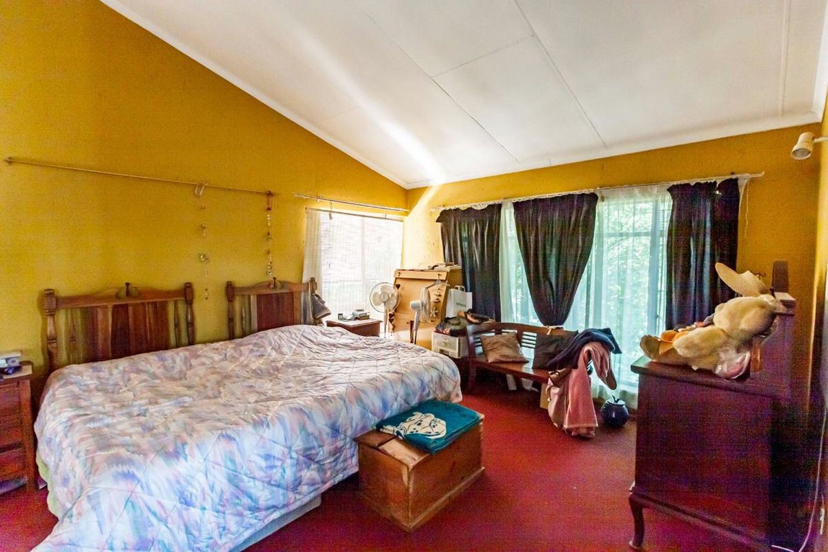 Spacious bedroom featuring a vaulted ceiling and large windows, offering a bright atmosphere with potential for modern updates to finishes and flooring.