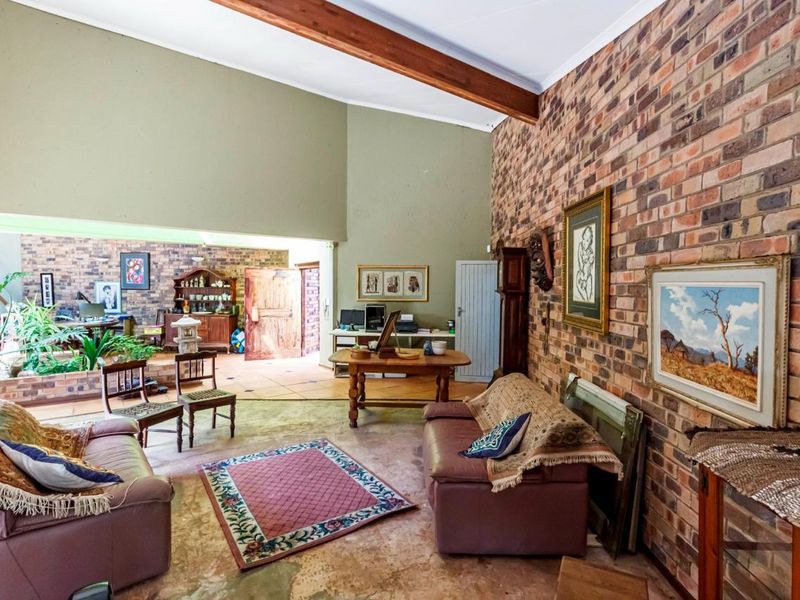 Spacious living area featuring a vaulted ceiling with exposed timber beams, a prominent face-brick feature wall, and an integrated indoor planter box.