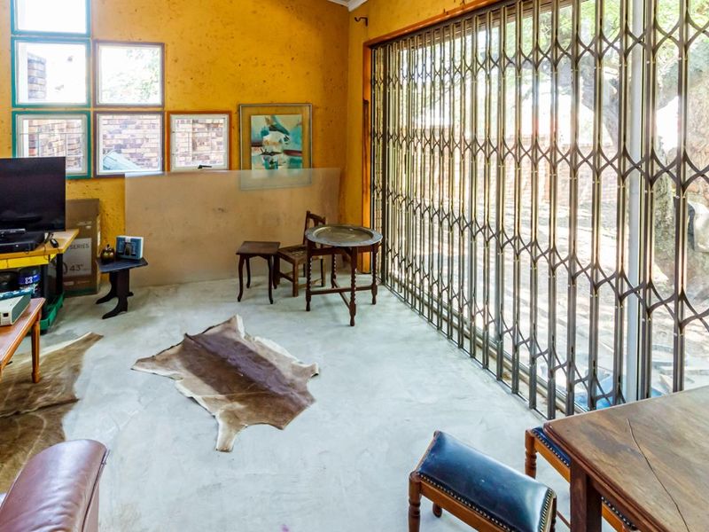 Living room featuring concrete flooring, large sliding glass doors with security gates, and multiple windows providing natural light.