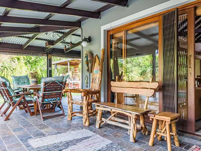 A spacious covered patio featuring slate tile flooring, a timber pergola structure, and large sliding glass doors providing seamless access to the interior living area.
