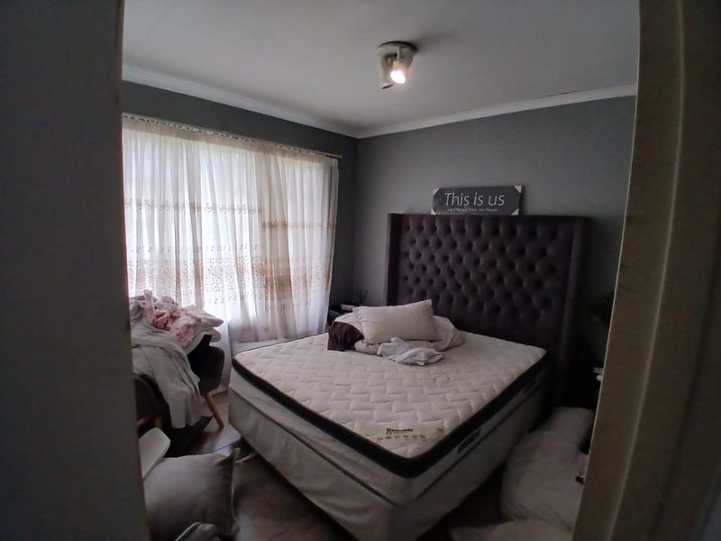 A bedroom featuring grey painted walls, a ceiling light fixture, and window curtains.