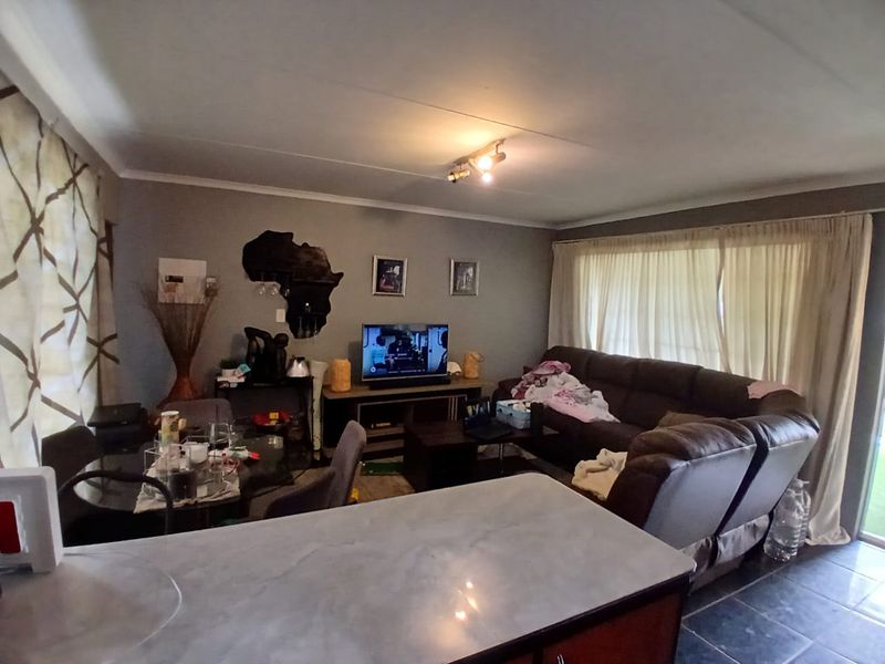 Open-plan living area featuring tiled flooring and a kitchen counter, providing a functional space for dining and relaxation.