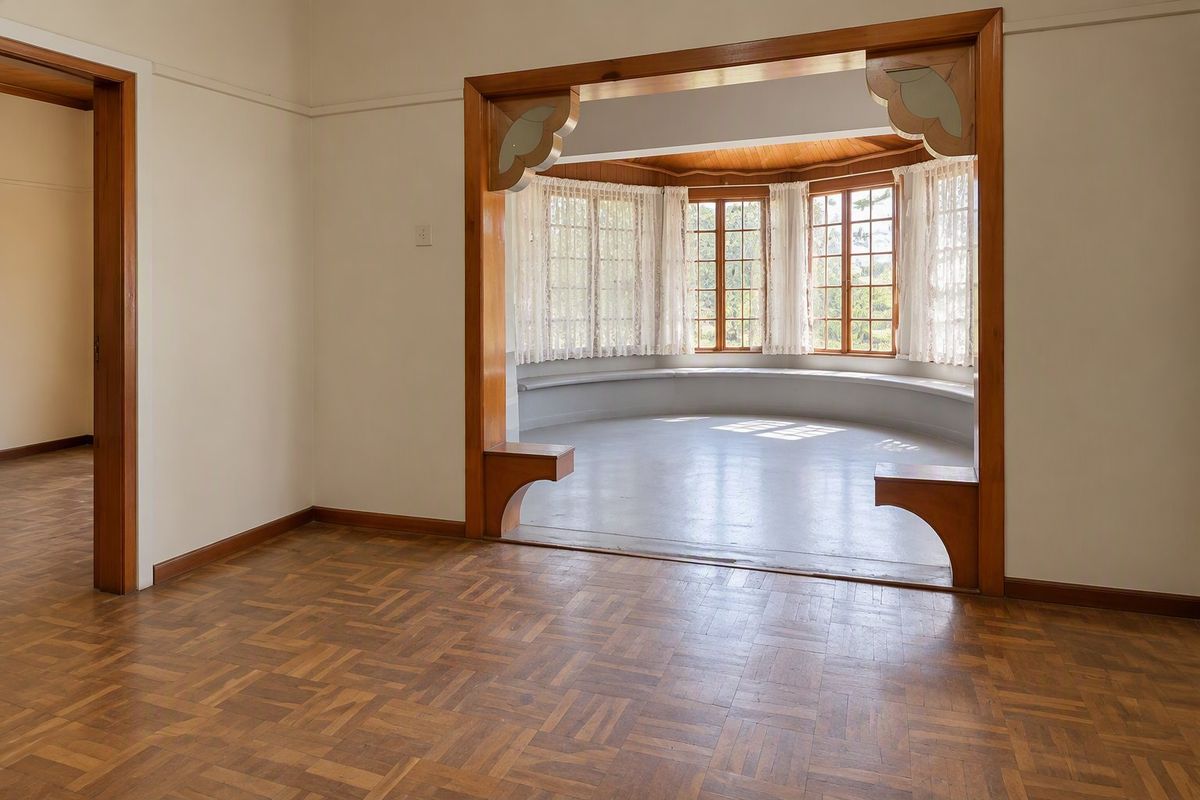 Spacious living area featuring classic parquet flooring, a decorative timber archway, and a charming bay window with a built-in seating area.