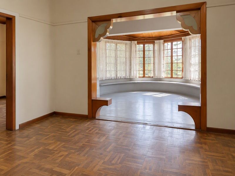 Spacious living area featuring classic parquet flooring, a decorative timber archway, and a charming bay window with a built-in seating area.