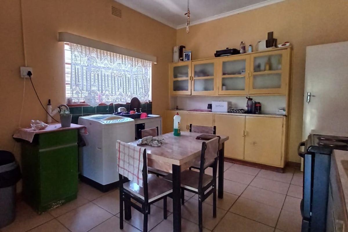 A dated kitchen featuring original built-in cabinetry, tiled flooring, and a functional layout, offering significant potential for a modern renovation.