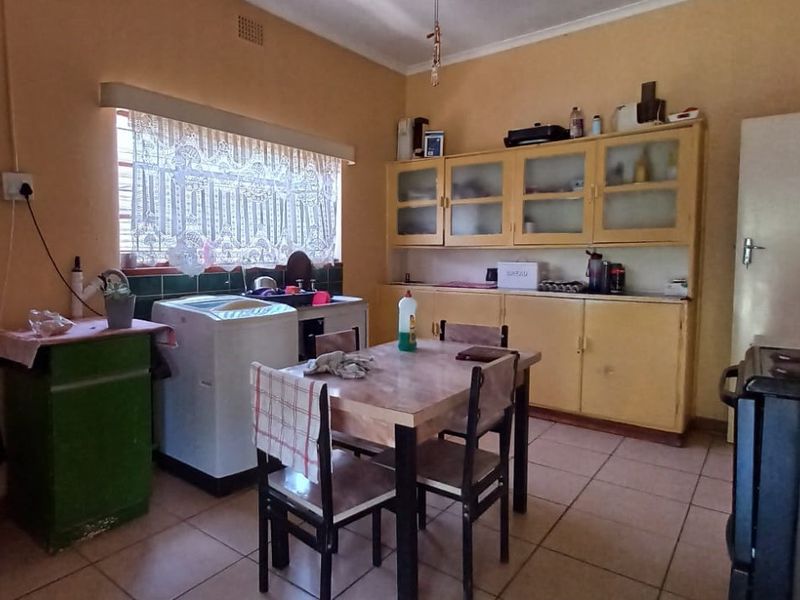 A dated kitchen featuring original built-in cabinetry, tiled flooring, and a functional layout, offering significant potential for a modern renovation.