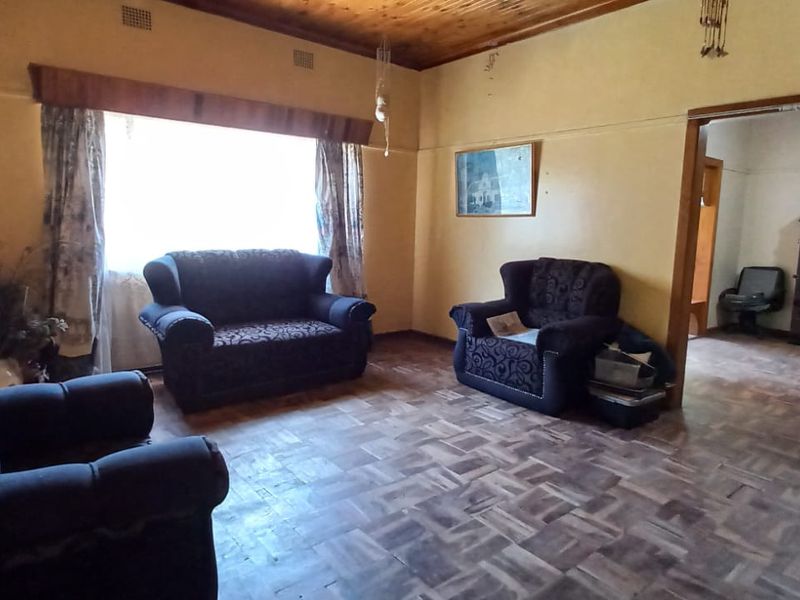 A living room featuring traditional parquet flooring and a timber ceiling, offering a dated aesthetic with potential for modernization.