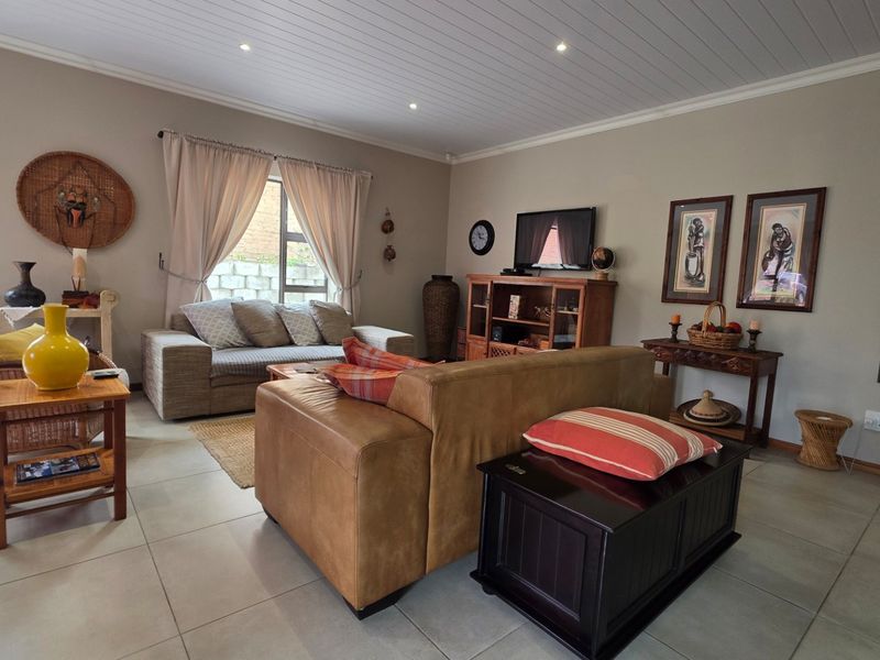 A comfortable living room featuring tiled flooring, recessed downlighting, and a tongue and groove ceiling, offering a warm and inviting atmosphere.