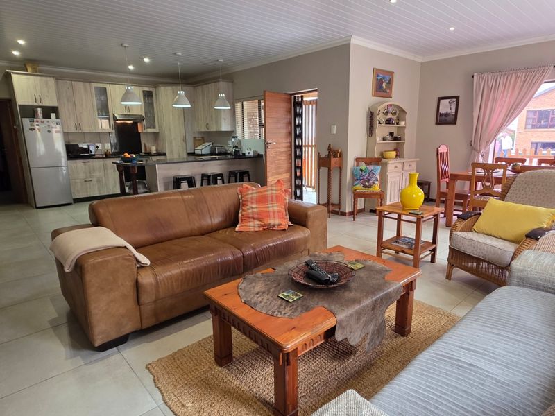 Spacious open-plan living area featuring a modern kitchen with island, tiled floors, and integrated lighting, creating a functional and inviting family space.