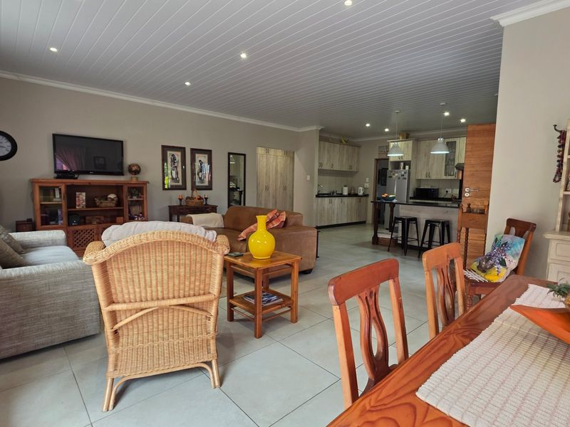 Spacious open-plan living and dining area featuring tiled floors, recessed lighting, and a functional kitchen with built-in cabinetry and a central island.