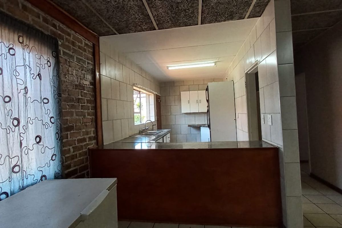 A dated kitchen featuring exposed brick walls, tiled backsplash, and a breakfast counter, offering potential for a modern renovation.