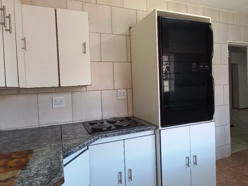 A functional kitchen featuring built-in cabinetry, granite countertops, an integrated electric hob, and a built-in double oven with tiled splashbacks.