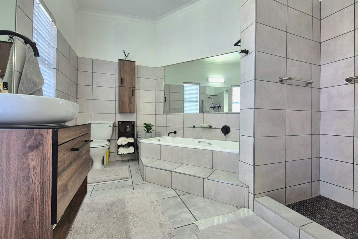 Modern bathroom featuring a built-in vanity with vessel sink, a tiled walk-in shower, and a built-in bathtub with large wall mirror.