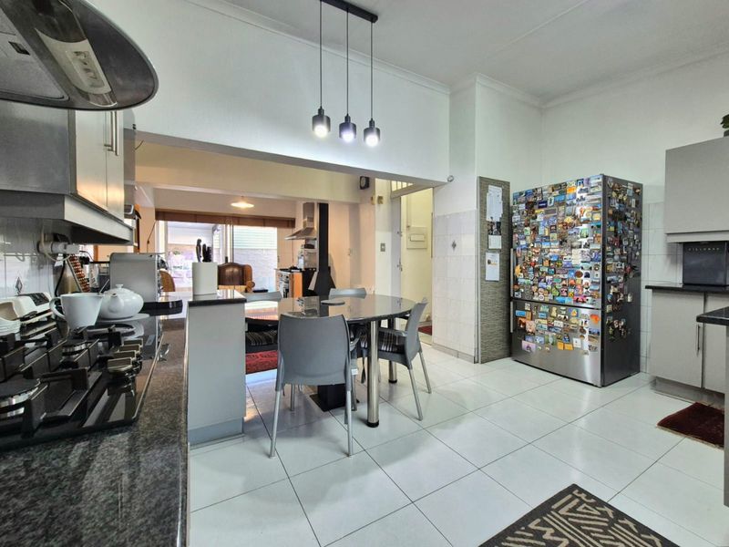 Open-plan kitchen and dining area featuring modern cabinetry, granite countertops, gas hob, and tiled flooring, creating a functional and connected living space.
