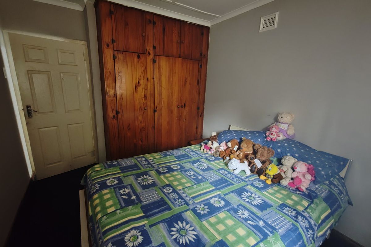 A bedroom featuring a large built-in wooden wardrobe, coving, and neutral wall finishes.