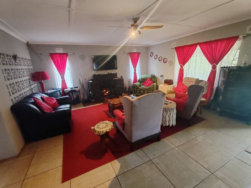 A living room featuring a stone fireplace, tiled flooring, and a ceiling fan, offering a traditional layout with ample space for seating.