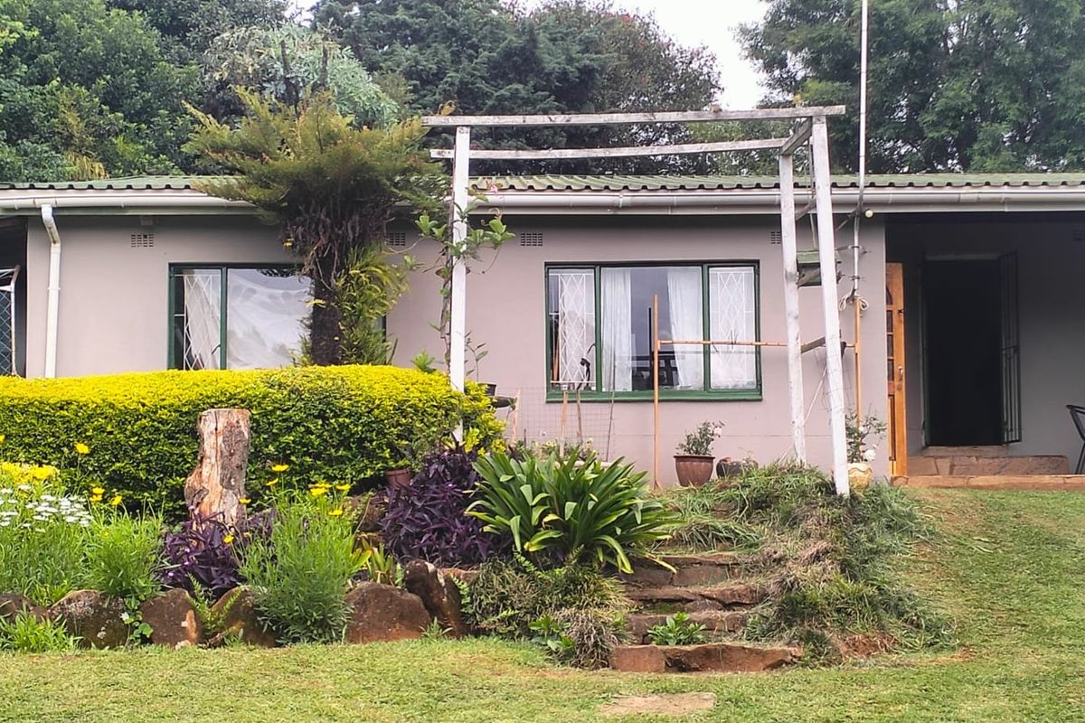 Rear view of the property featuring a garden, stone steps, and a pergola structure attached to the exterior wall.
