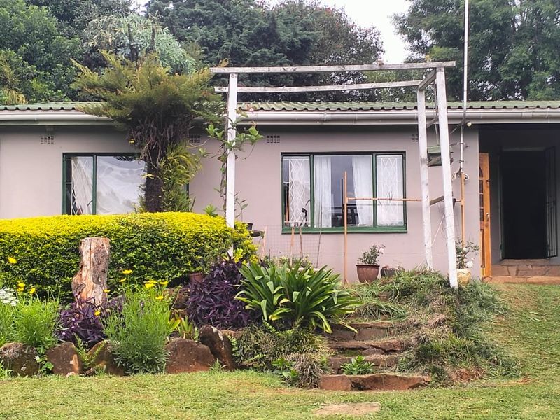 Rear view of the property featuring a garden, stone steps, and a pergola structure attached to the exterior wall.