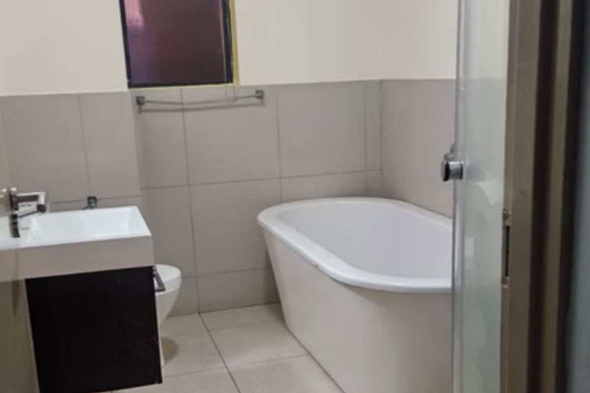 A clean, modern bathroom featuring a freestanding bathtub, wall-mounted vanity, and neutral ceramic tiling throughout.