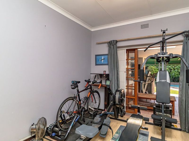 A dedicated home gym space featuring laminate flooring and sliding glass doors that provide direct access to the outdoor patio area.
