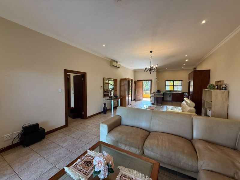 Spacious open-plan living and kitchen area featuring tiled flooring, recessed lighting, and an integrated kitchen layout with an island.