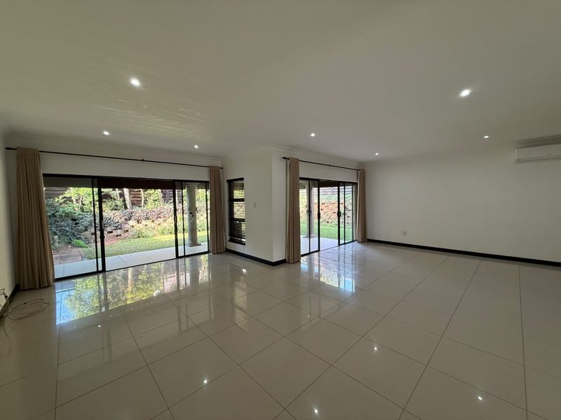 Spacious, light-filled living area featuring large sliding glass doors, polished porcelain tiles, and recessed lighting, offering seamless access to the rear garden.