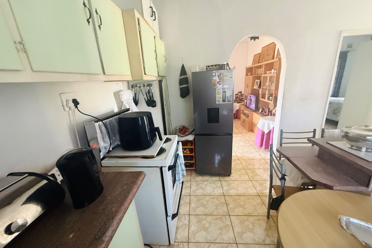 A functional kitchen featuring built-in cabinetry, tiled flooring, and an arched doorway leading to the adjacent living area.