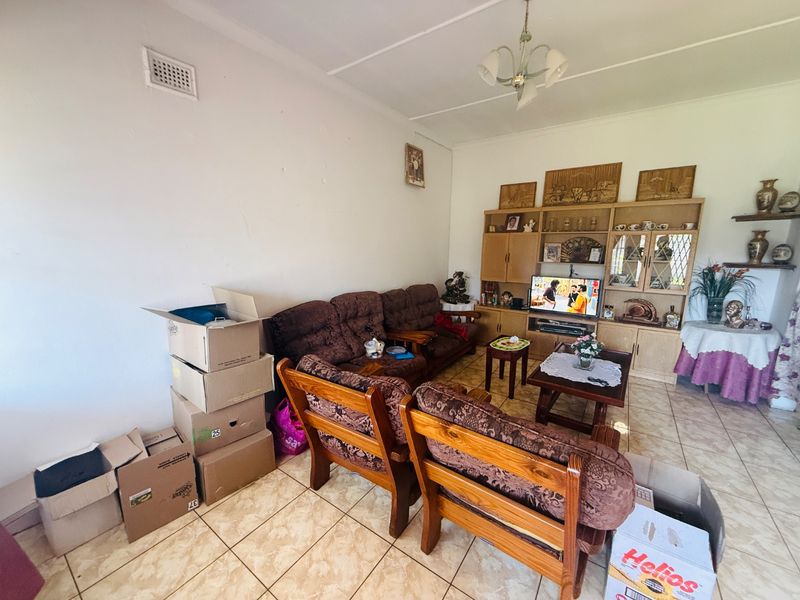 A living room featuring ceramic tile flooring and a large built-in wooden wall unit, offering potential for modernization and updated interior finishes.