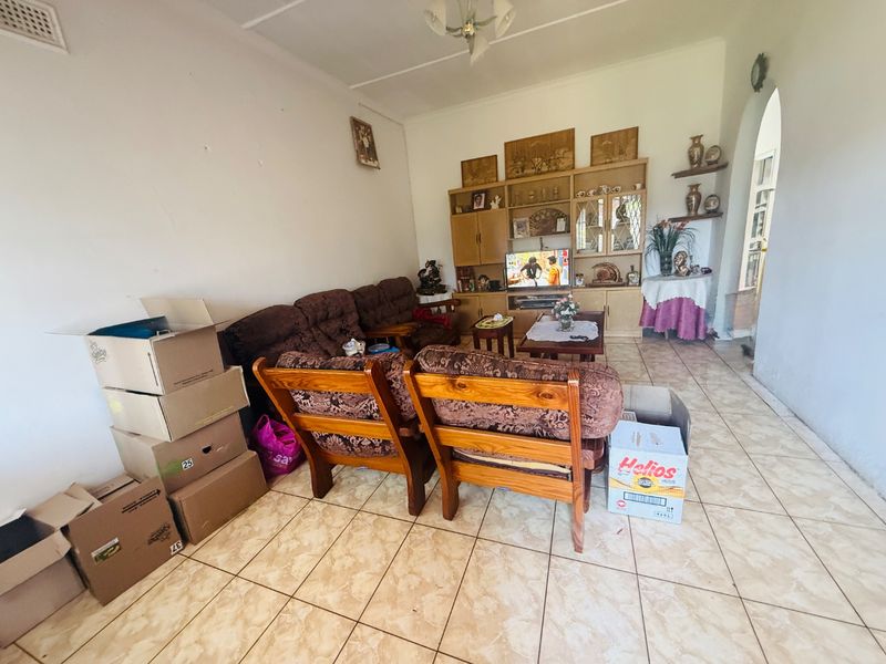 A living room featuring tiled flooring and a large built-in wooden wall unit, offering a functional space for relaxation and storage.