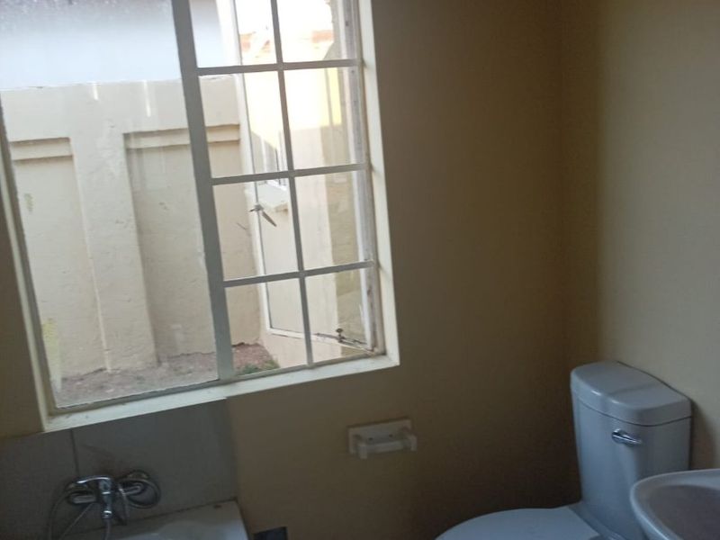 A functional bathroom featuring a bathtub, toilet, and washbasin, with natural light provided by a window overlooking the exterior area.