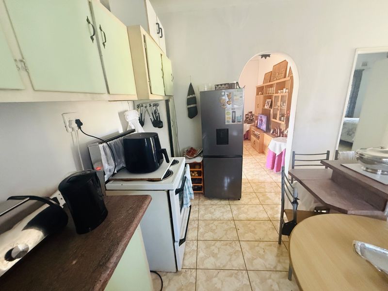 A functional kitchen featuring built-in cabinetry and tiled flooring, leading through an archway into the adjacent living area.