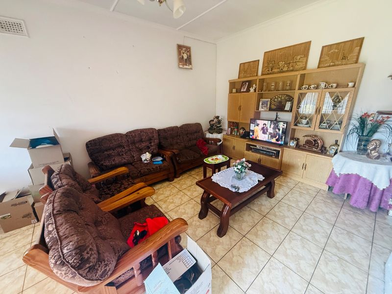 A living room featuring ceramic floor tiles and a large built-in wooden wall unit, offering a functional space with potential for modern updates.