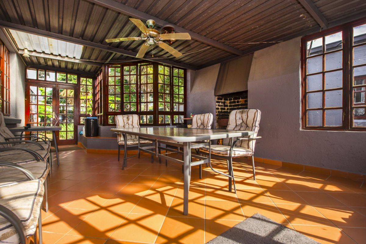 Covered patio area featuring tiled flooring, a built-in fireplace, and a ceiling fan, providing a functional outdoor entertainment space.