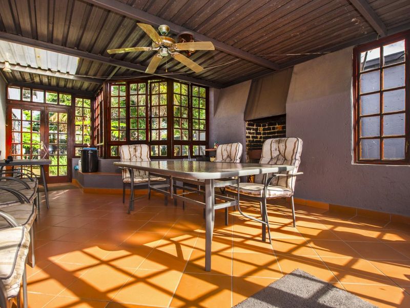 Covered patio area featuring tiled flooring, a built-in fireplace, and a ceiling fan, providing a functional outdoor entertainment space.